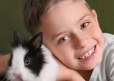 A young boy gently holding a fluffy rabbit in his arms.